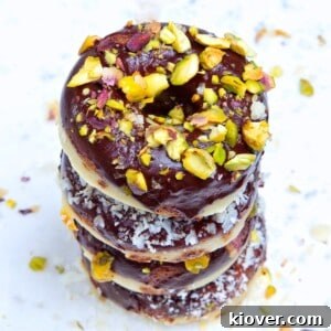 10 Healthy Baked Goods Kids Will Love 11 Four delicious chocolate doughnuts stacked on a white marble background with pistachio and coconut toppings.