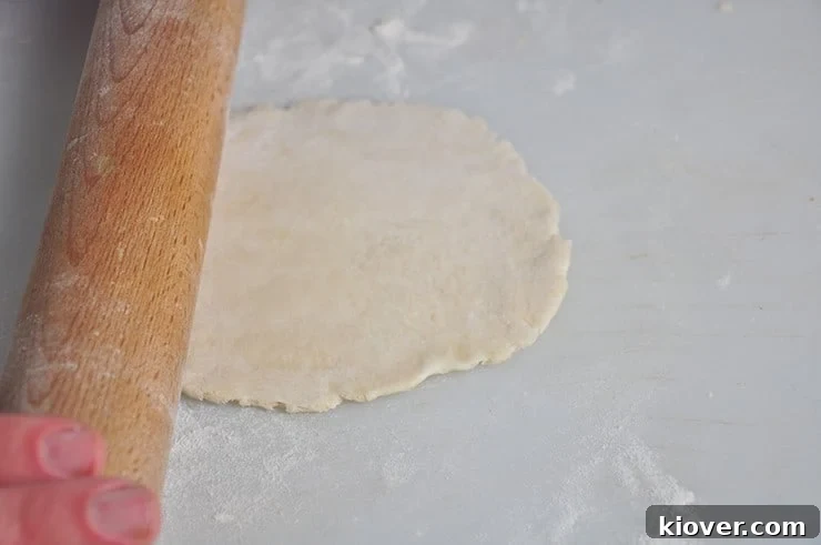 A flat, thinly rolled flour tortilla resting on a wooden cutting board, ready for cooking.
