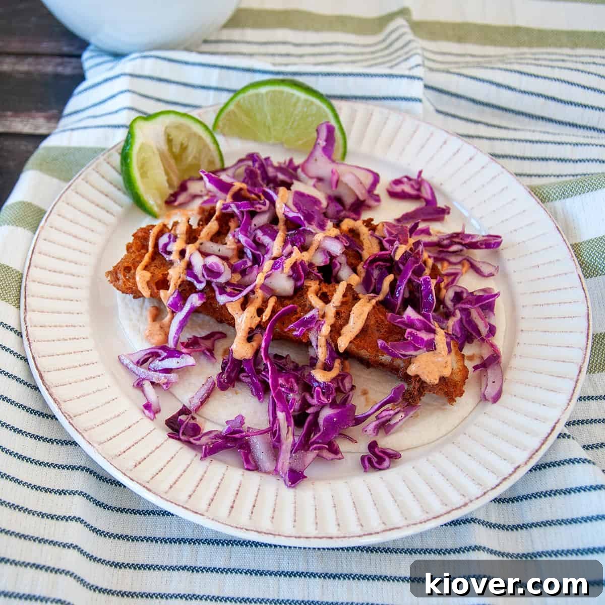 Crispy Beer Battered Fish Taco with cabbage and sriracha baja sauce, beautifully presented.