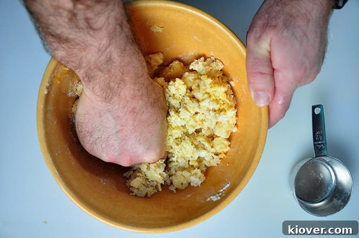 Using hand to smoosh the thawed tater tots, egg, and flour together.