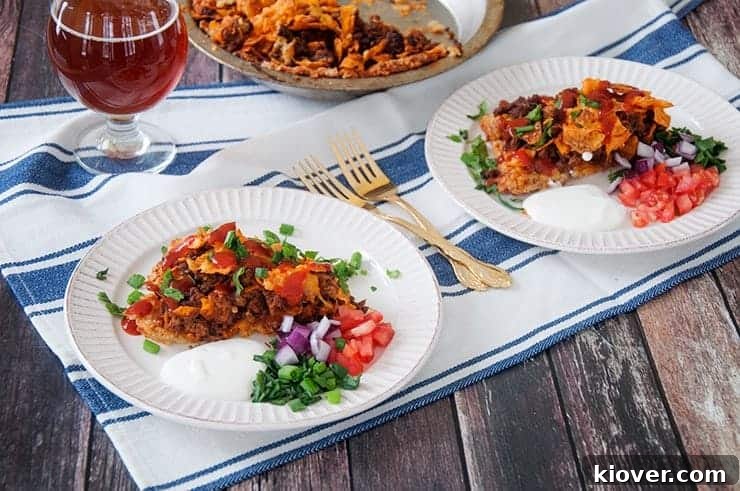 Side View of two plates of the Dorito pie. Two gold forks and a beer off to the side.