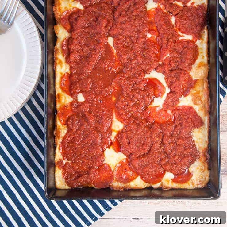 Overhead picture of a full pan of Detroit Style Pizza, showcasing its thick crust, rich sauce, and perfectly melted, cheesy edges.