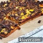 Detroit Style Coney Island pizza on a brown paper mat, showcasing its delicious texture.