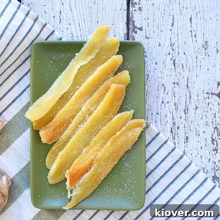 Delicious dried candied ginger pieces arranged on a vibrant green plate, placed on a clean white table, ready to be enjoyed as a sweet and spicy treat.