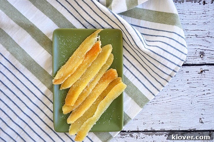 Close-up of perfectly candied ginger pieces, dusted with sugar, arranged on a green plate, showcasing their inviting texture and color.