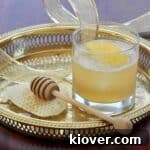 Gold Rush Cocktail on a Gold Platter with honey and a honey dipper to the side