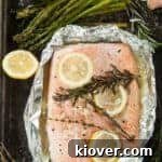 Overhead view of a tin foil grilled salmon fillet recipe, still in foil and some asparagus on the side.