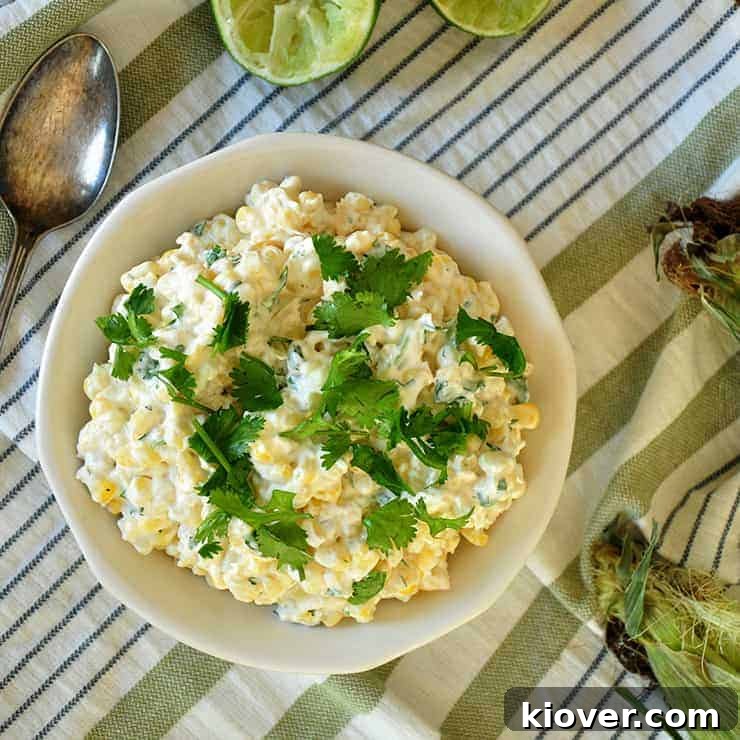Overhead view of perfectly grilled Mexican street corn (Elote) in a bowl, garnished with fresh cilantro and lime wedges.