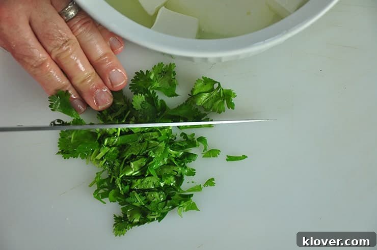 A close-up of fresh cilantro being finely chopped on a wooden cutting board, ready for use in the Mexican corn recipe.