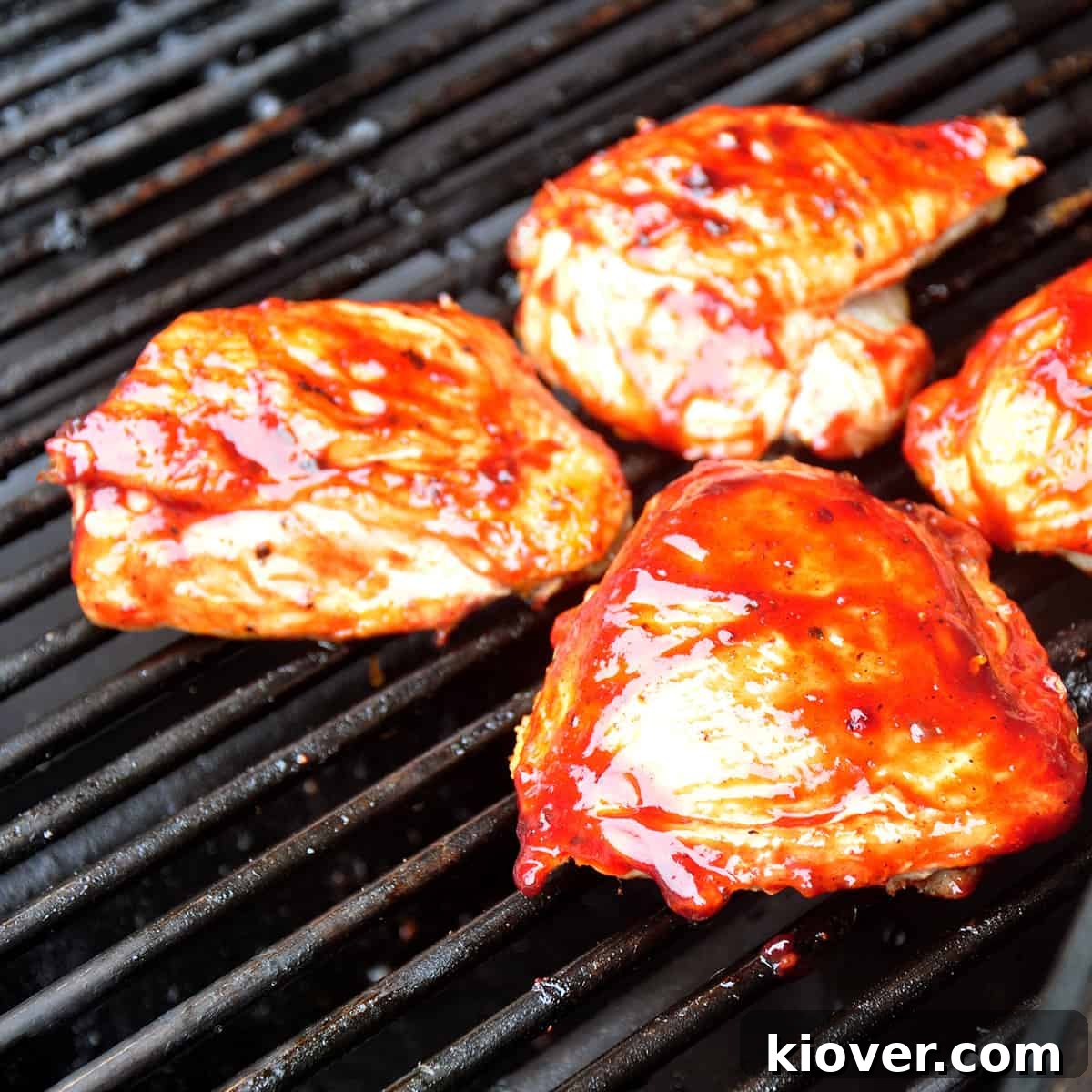 Three barbecue chicken thighs on a grill.