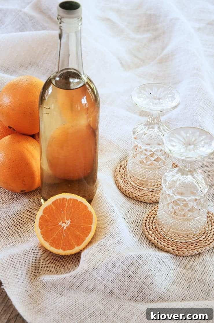 Orangecello A bottle of orangecellow with a half orange showing in front of the bottle. Two glasses are showing.