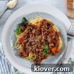 Traditional Pasta Sauce Recipe served over Spaghetti noodles on a white plate with garlic bread and cheese on the side
