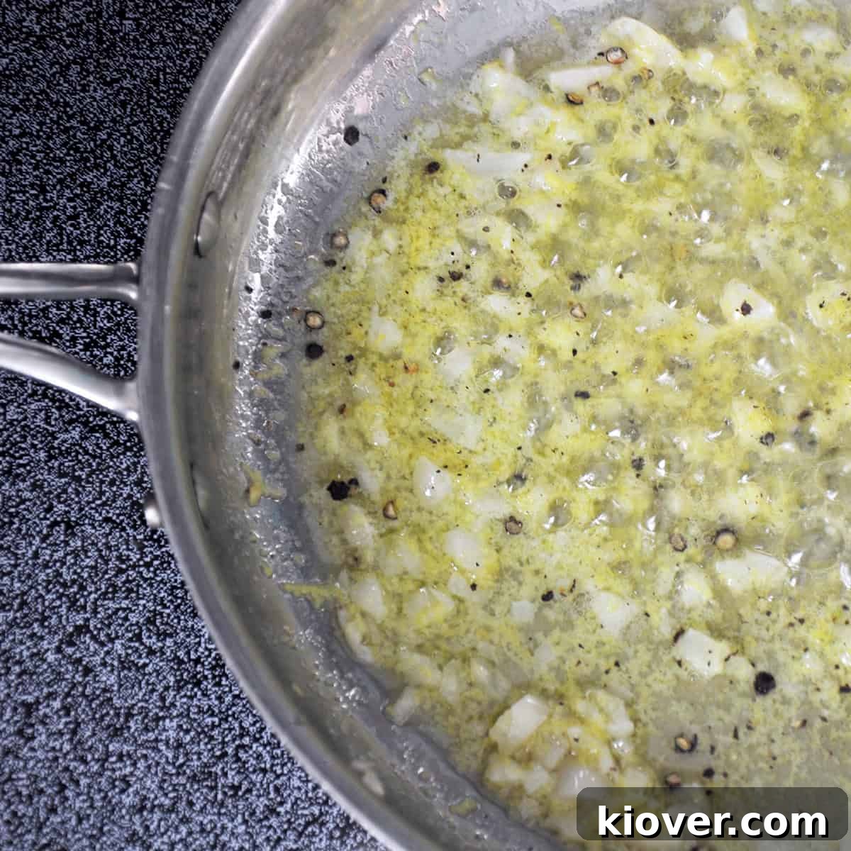 Butter, minced garlic, lemon zest, and freshly cracked pepper simmering gently in a metal saucepan, infusing flavors.