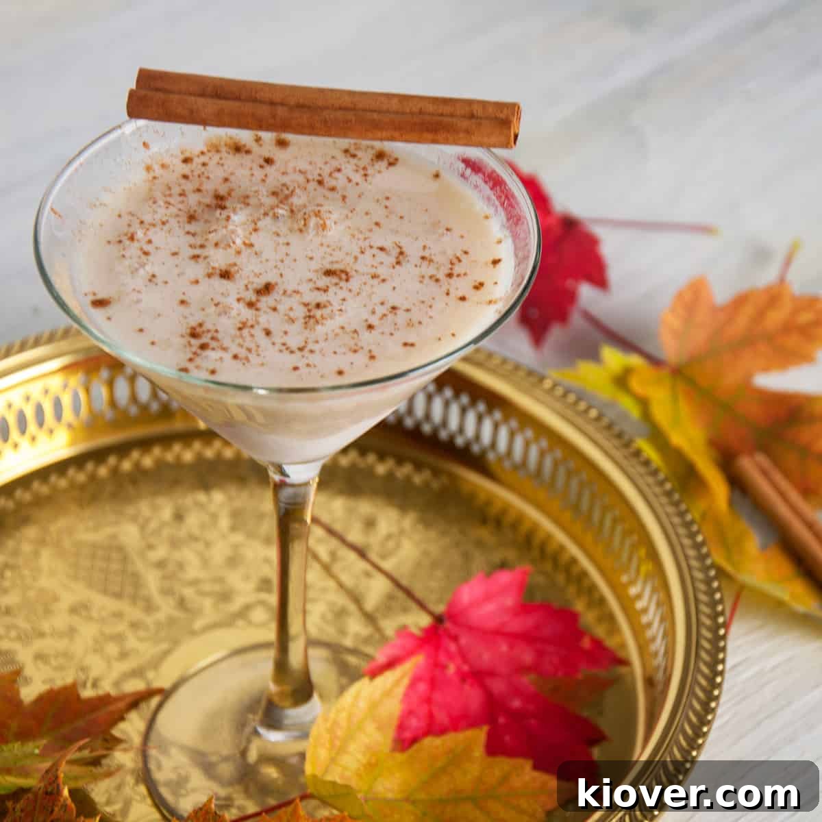 RumChataTini cider cocktail on a gold platter with Fall leaves garnishing the scene.