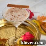 RumChataTini cider cocktail on a gold platter with Fall leaves garnishing the scene.