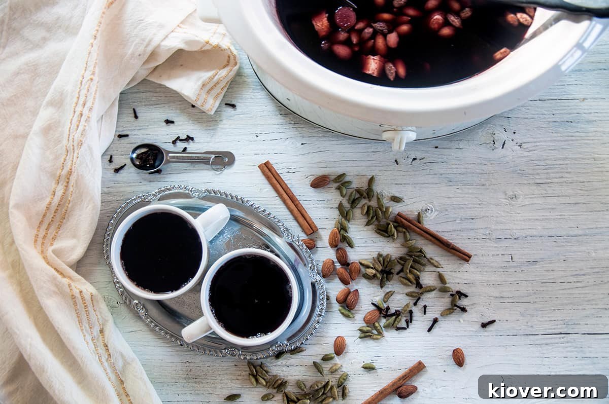 Glogg: A Great Holiday Recipe Two mugs of Glogg placed next to a slow cooker filled with the warm, spiced drink, ready for serving.