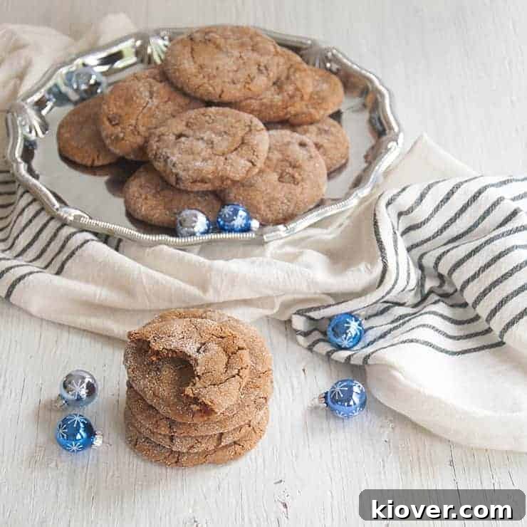 Soft Ginger Cookie Stack of Ginger Cookies with one that has a bite taken out of it and a platter of extras in the background.