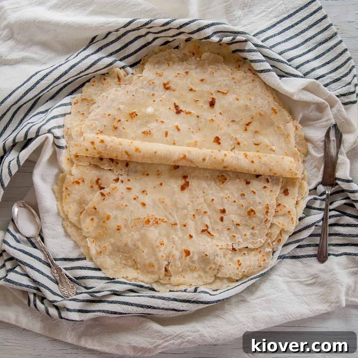 Flat lefse being rolled on a blue napkin, showcasing its thinness.