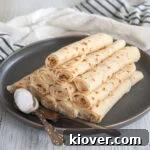 Pile of lefse from this lefse recipe on a dark plate with a knife and a spoonful of sugar.