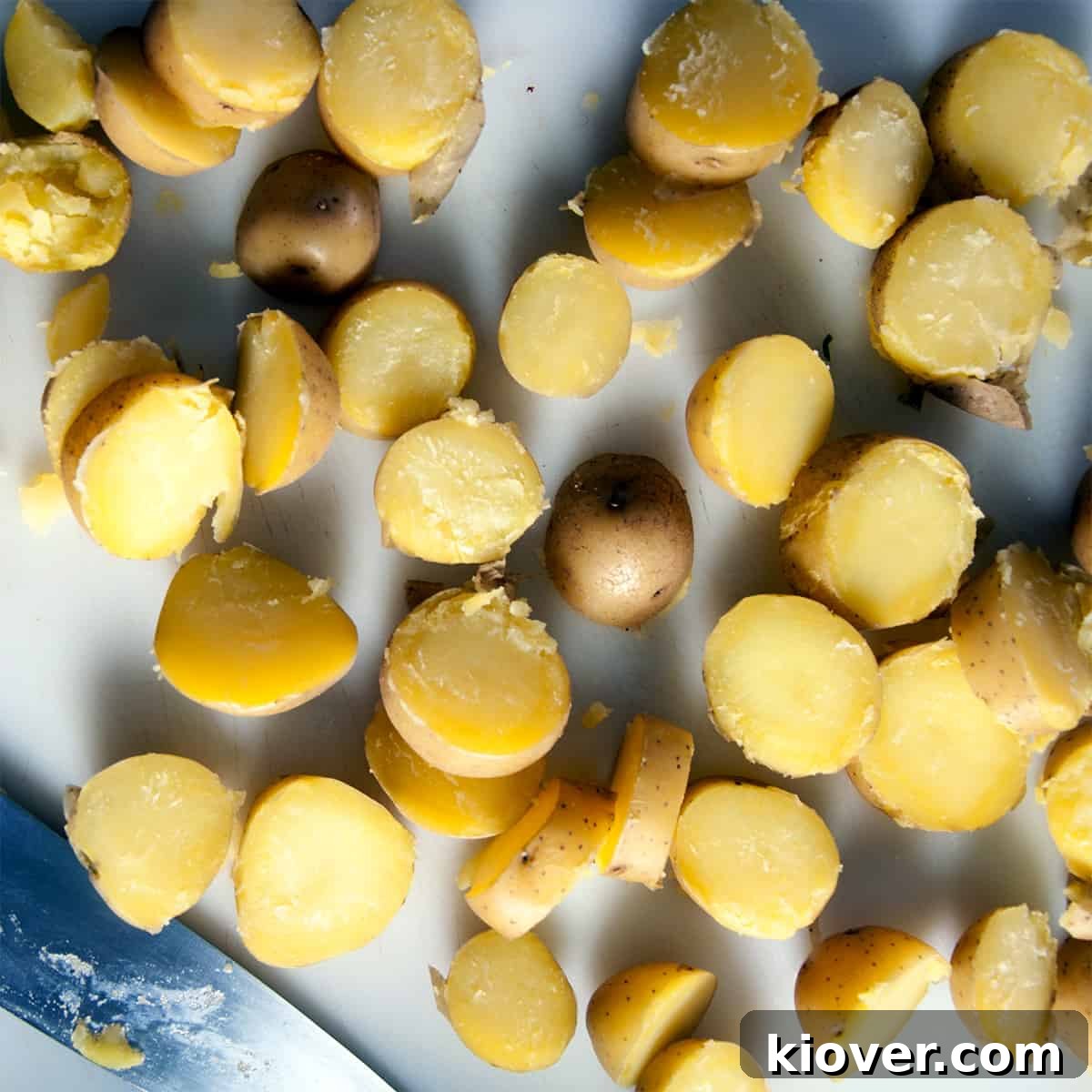 Freshly boiled Yukon potatoes on a wooden cutting board, ready to be sliced for German potato salad.