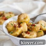 German Potato Salad (Kartoffelsalat) in a white bowl with a fork, ready to be served.