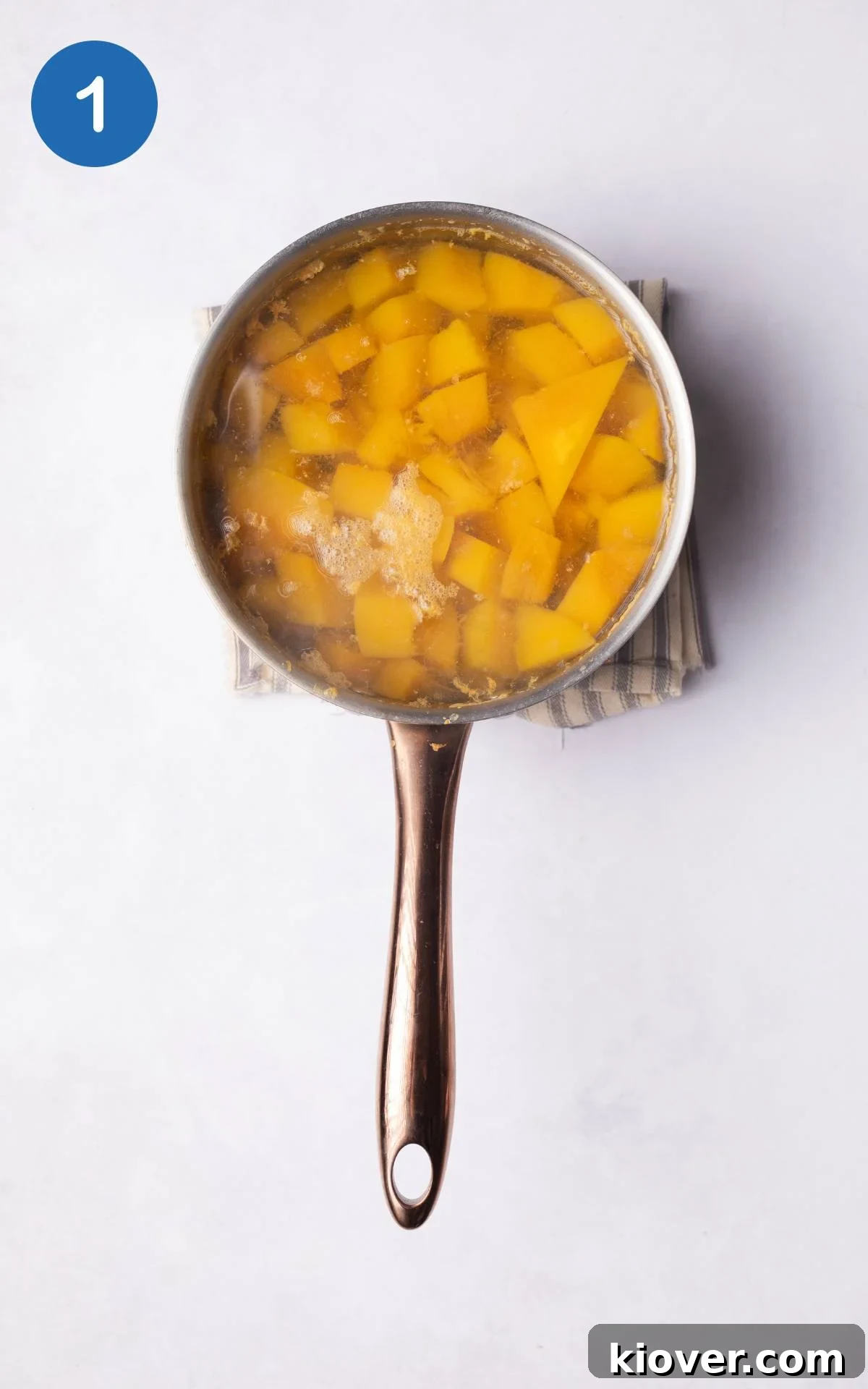 Pumpkin boiling in water in a pot on a stove.