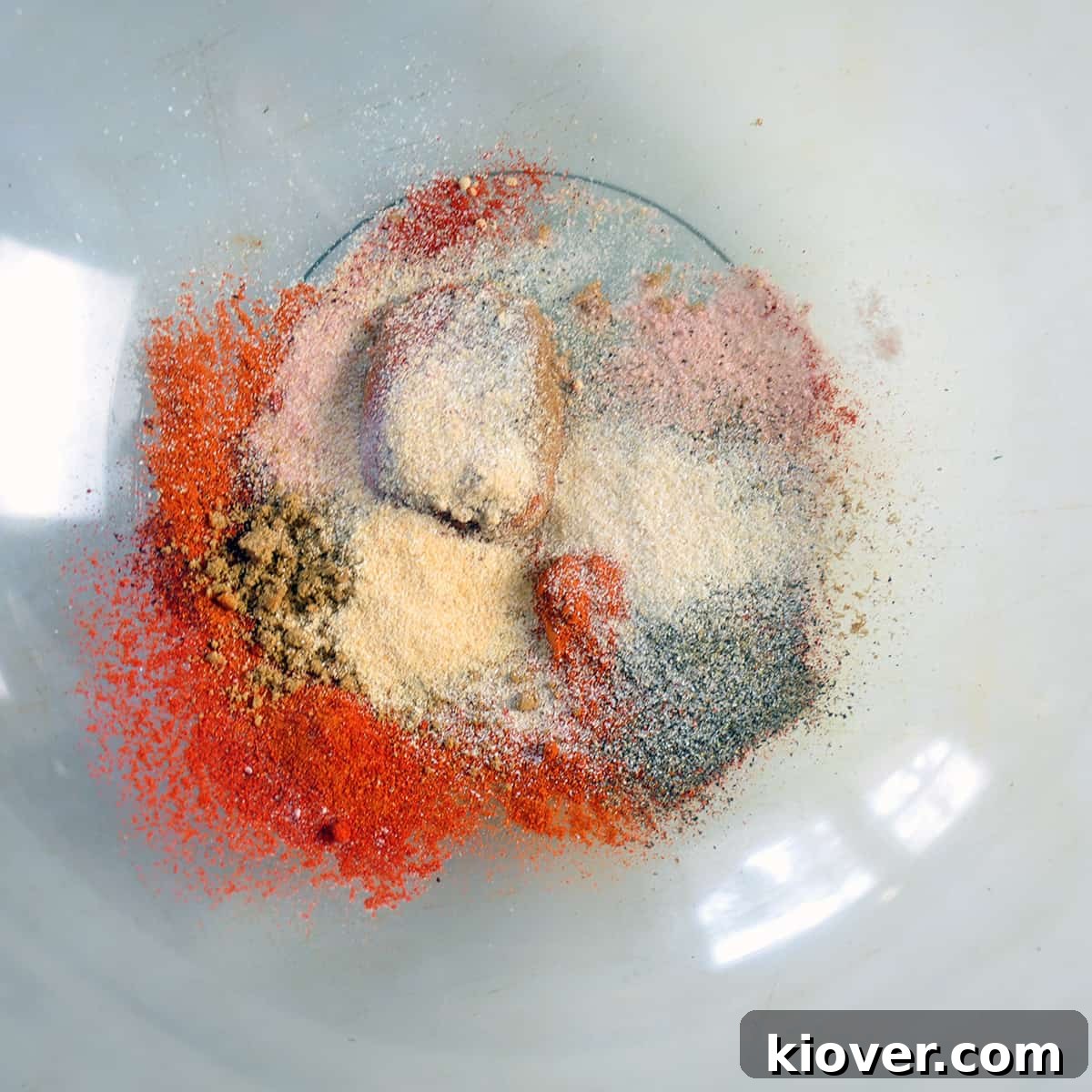 A variety of spices in a large glass bowl.