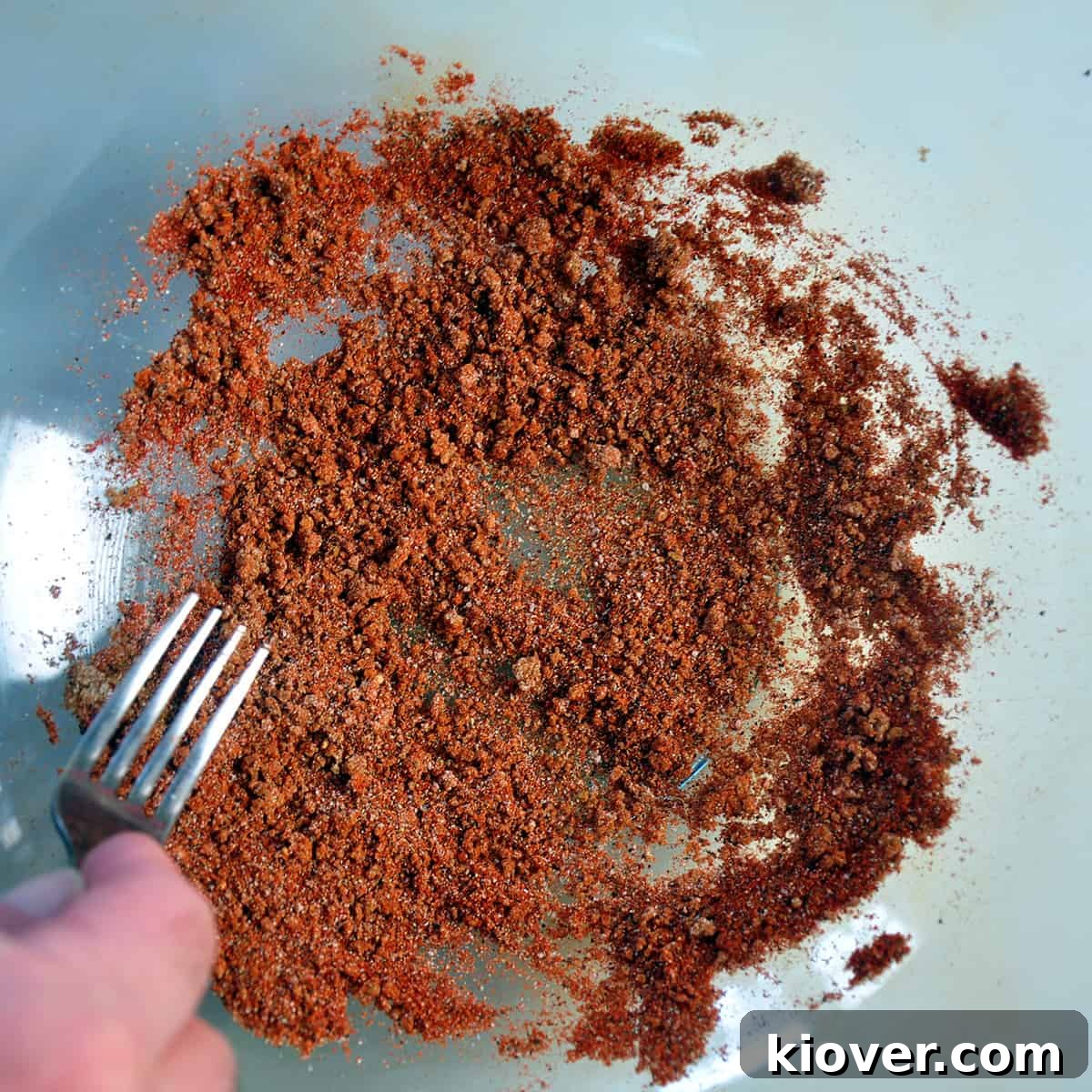 Mixing the powders with a fork in a glass bowl.