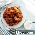10 Sweet and Spicy Dry Rub Chicken Wings on a white plate with chili lime dipping sauce to the side.