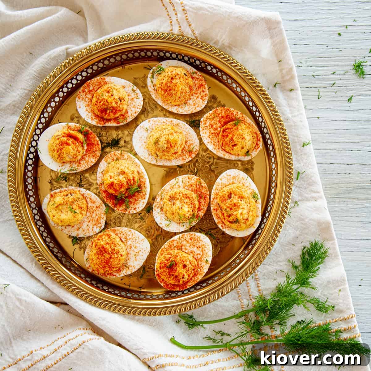 A Plate of Dill Pickle Spicy Deviled Eggs on a gold platter and dill on the side.