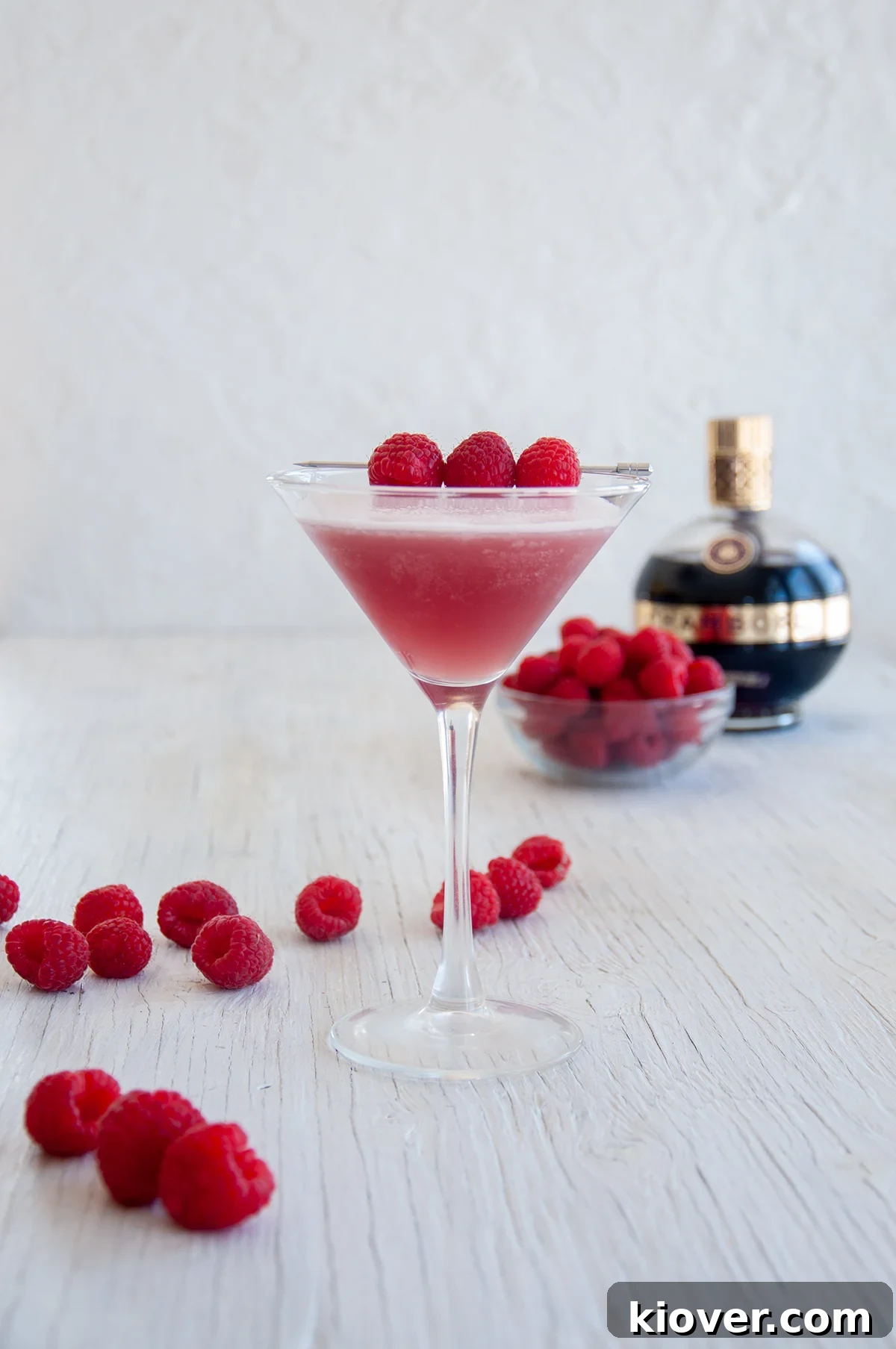 French Martini One French Martini on a white table with raspberries and a bottle of Chambord in the background, exuding elegance.