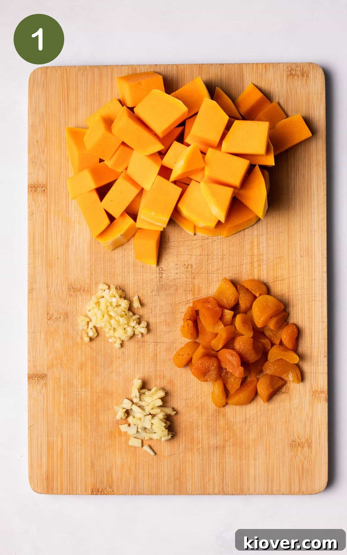 Golden Butternut Curry 4 Chopped butternut squash, crushed garlic, and halved apricots on a wooden cutting board, prepped for curry.