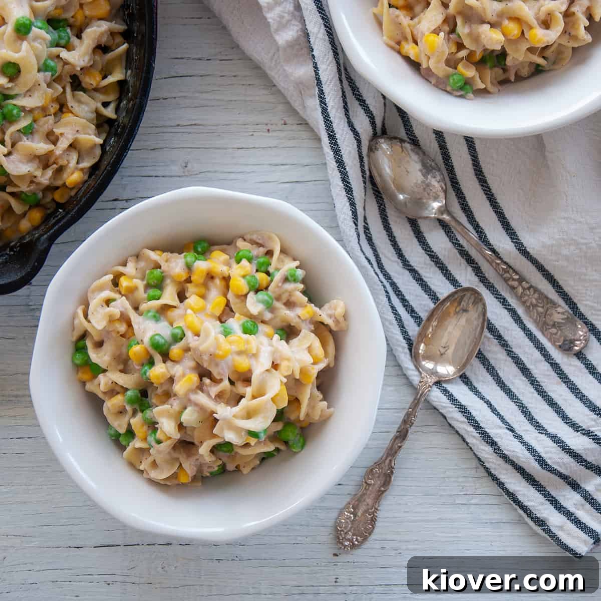 Quick Homemade Tuna Pasta Skillet 2 Two white bowls filled with Homemade Skillet Tuna Helper and two silver spoons on a white and blue cloth.