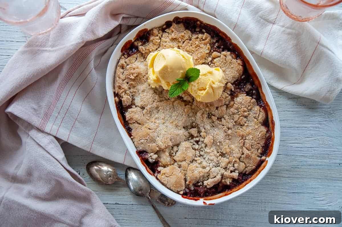 Sweet and Tart Strawberry Rhubarb Cobbler 4 Overhead view of a 1.5 Quart Baking dish filled with a freshly baked Strawberry Rhubarb Cobbler, adorned with two melting scoops of vanilla ice cream and a sprig of fresh mint.