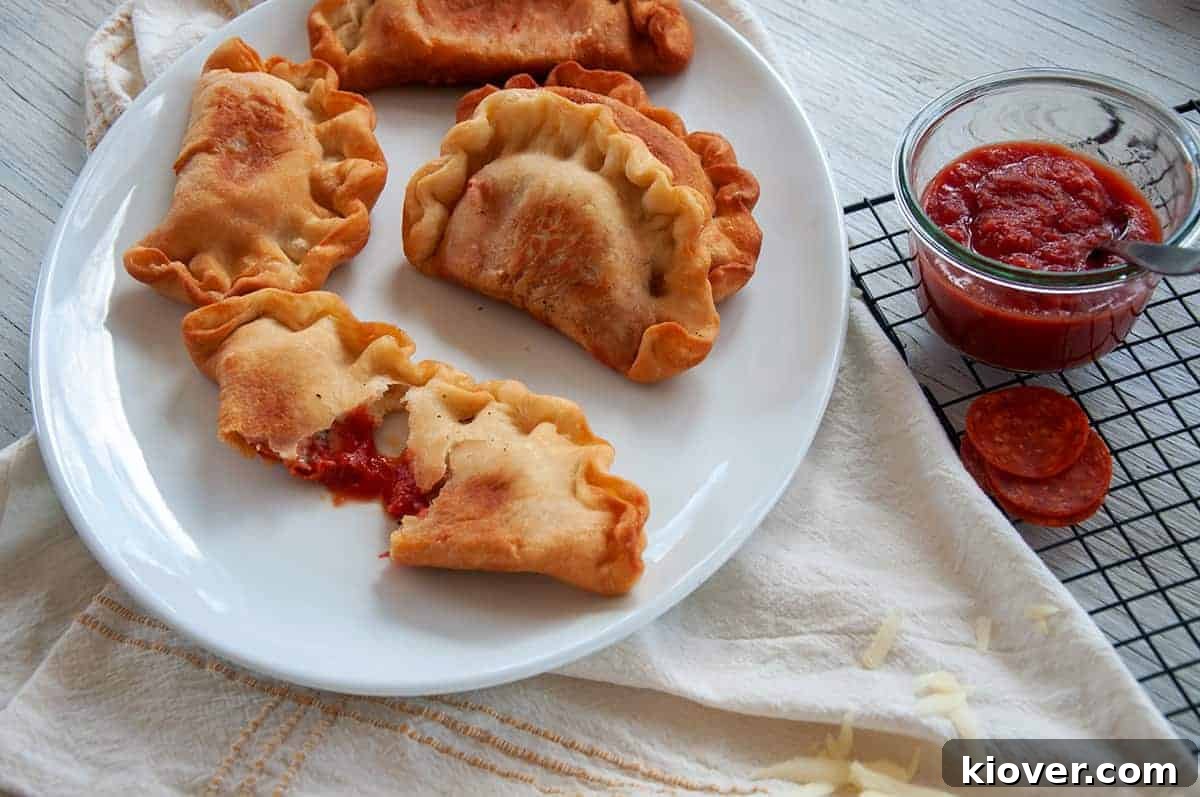 A large plate filled with four perfectly fried Panzerotti, one of which is pulled apart to reveal its delicious, melted cheese and pepperoni filling.