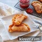 Two fried Italian Panzerotti on a white plate with a fork to the side.