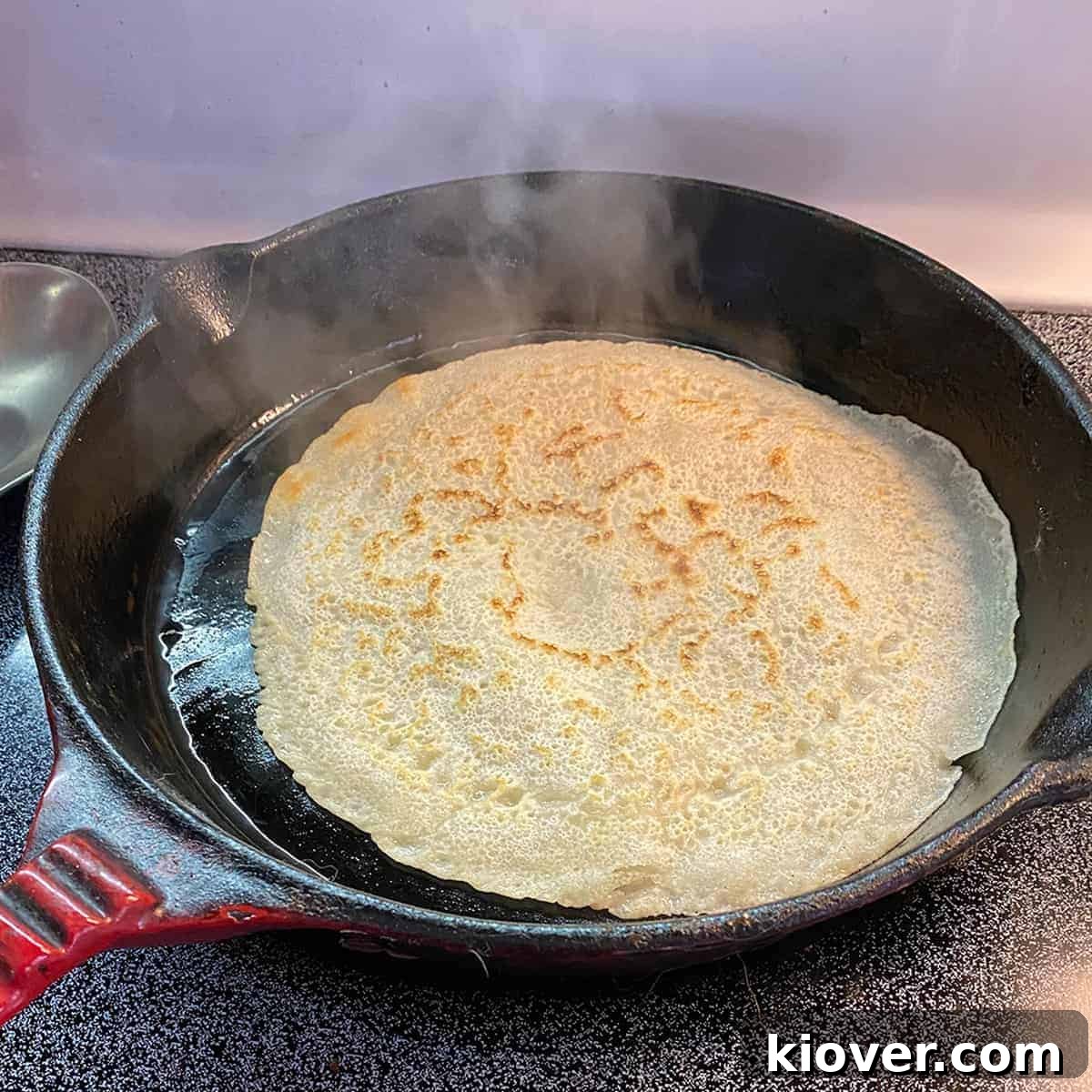 Flipped Testaroli A single testaroli cooking in a cast iron, after having been flipped.