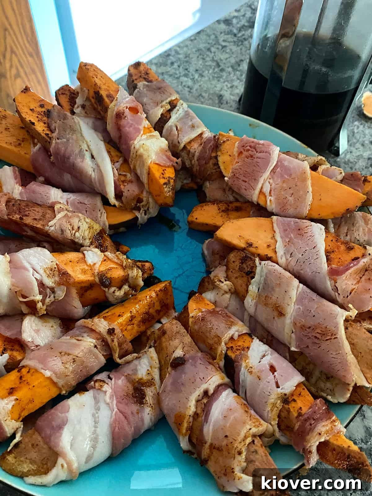 Smoky Bacon-Wrapped Grilled Sweet Potato Sticks 4 A process picture capturing an array of sweet potato fries, each meticulously wrapped in bacon, neatly arranged on a plate and poised for their journey to the grill.