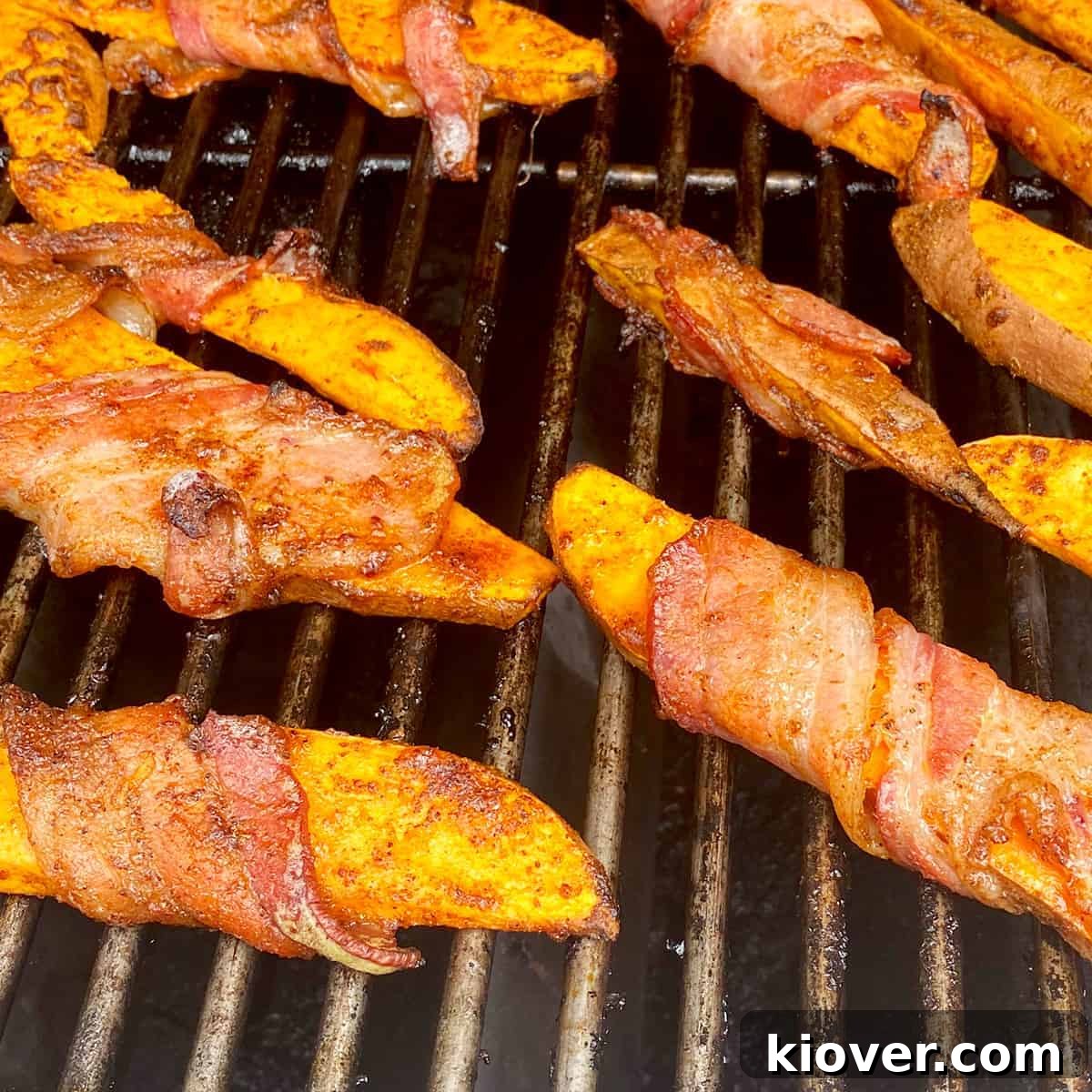Smoky Bacon-Wrapped Grilled Sweet Potato Sticks 5 Bacon-wrapped sweet potato fries sizzling gently on the grill, positioned over indirect heat, achieving a perfect golden crispness.
