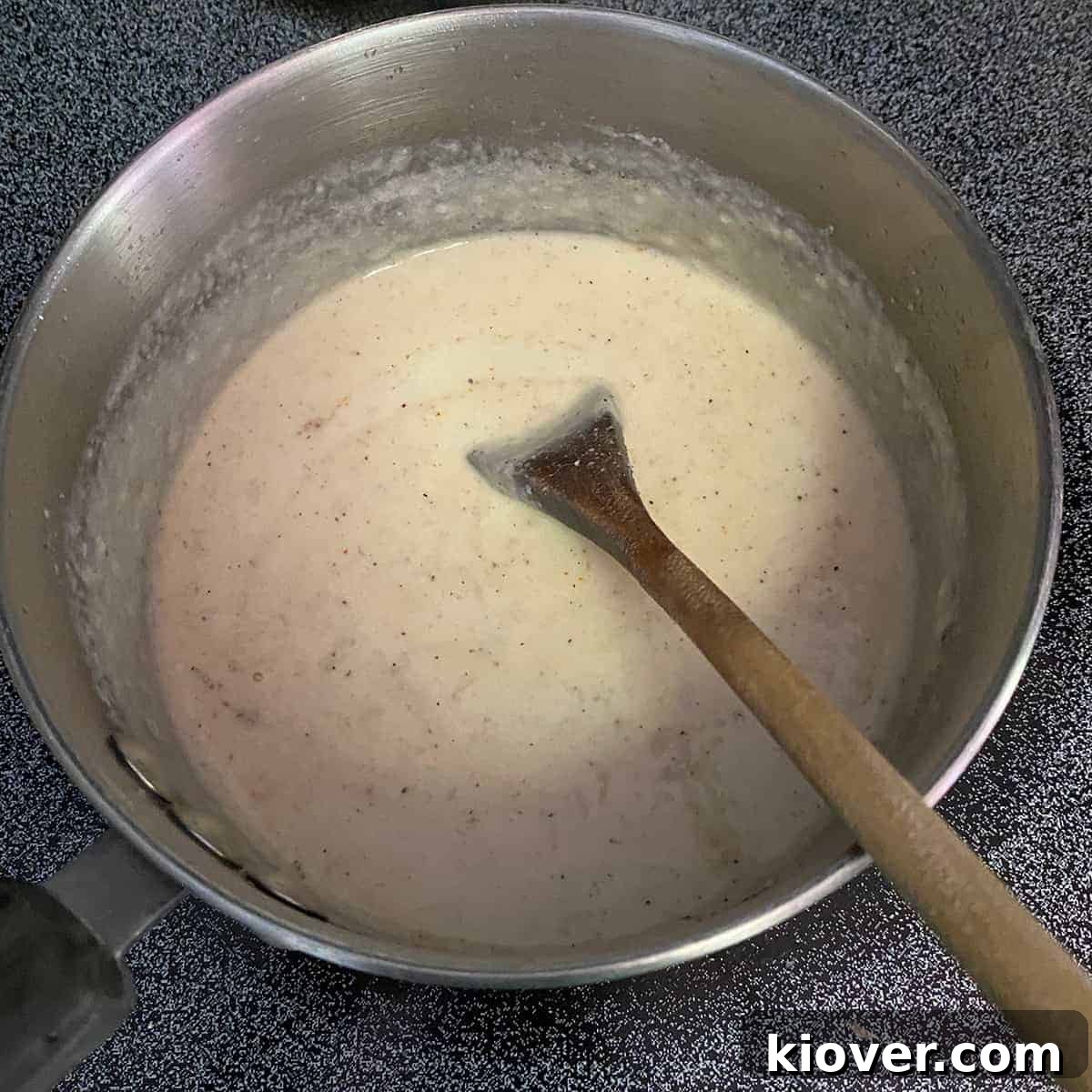 Saucepan with completed mornay sauce and a wooden spoon in the dish.
