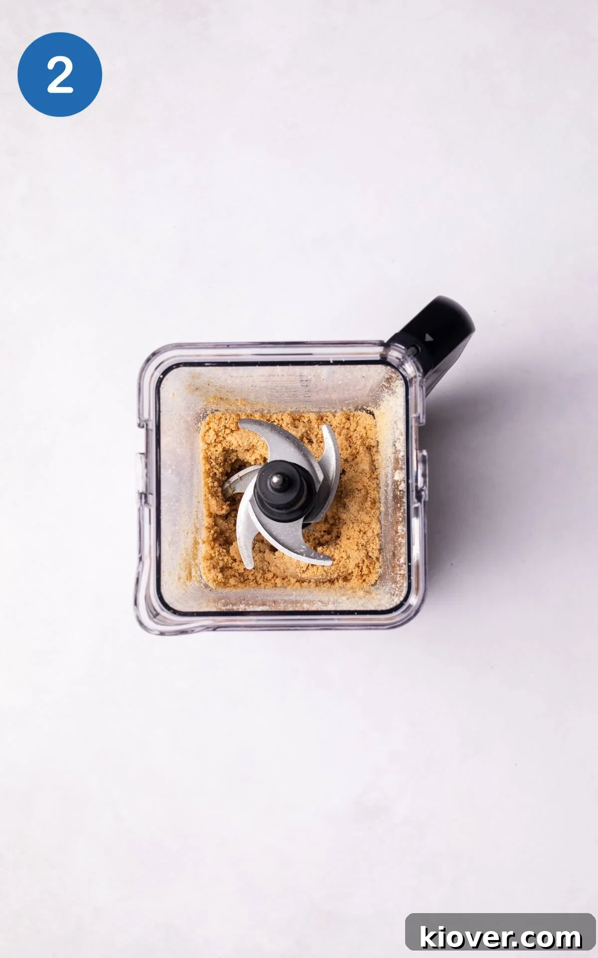 Roasted hazelnuts being blended in a food processor, turning into fine crumbs.
