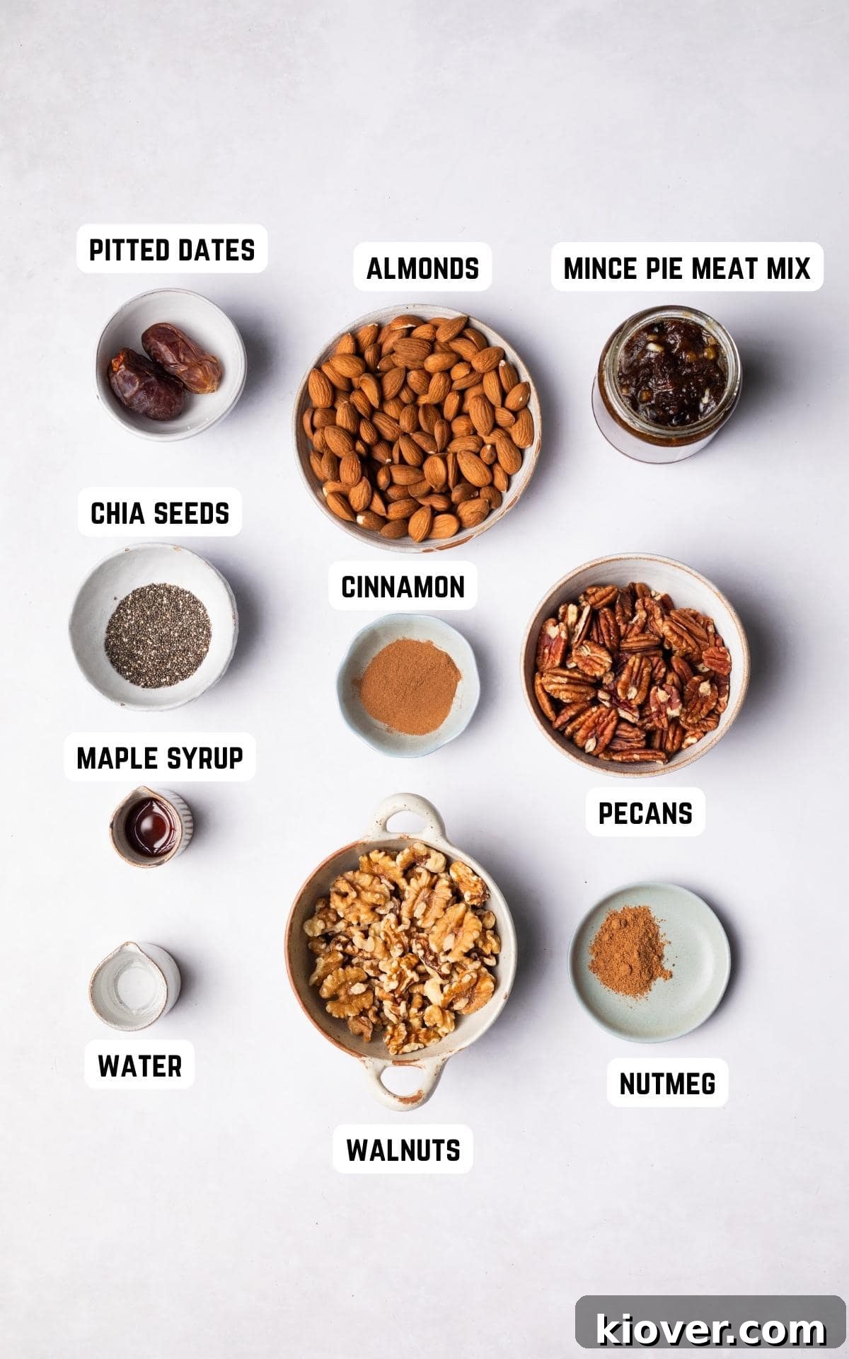 Assortment of fresh ingredients laid out on a wooden surface, including walnuts, almonds, pecans, dates, chia seeds, cinnamon, nutmeg, and maple syrup, ready for making healthy mince pies.