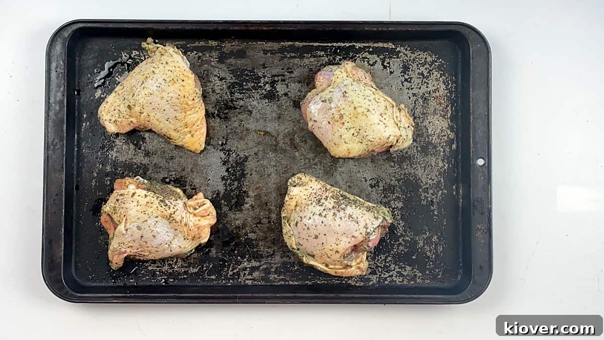 Four uncooked chicken thighs getting ready for the oven.