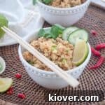 A bowl of Crab Fried Rice in a white bowl that is garnished with cilantro, cucumbers, lime.