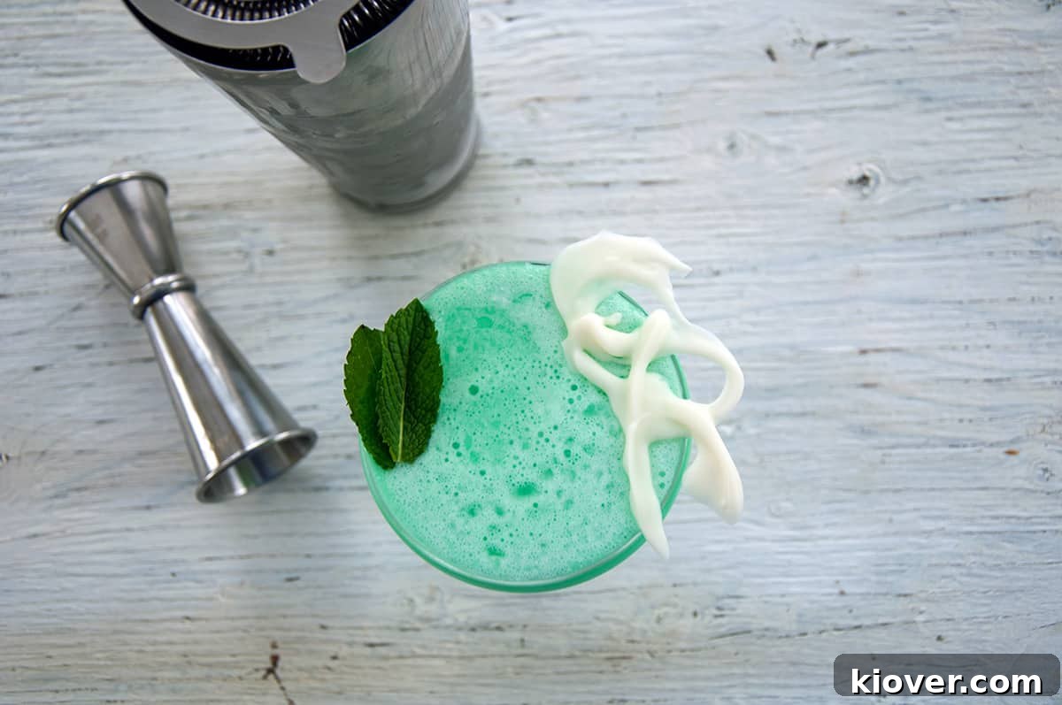 An inviting overhead view of a freshly made Grasshopper cocktail in a coupe glass, with a professional measuring jigger resting beside it, highlighting the preparation.