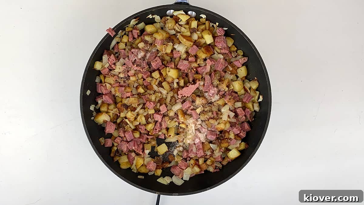 Crispy Homemade Corned Beef Hash 5 A skillet filled with nearly complete corned beef hash, seasoned and almost ready to be served, showcasing its golden-brown texture.
