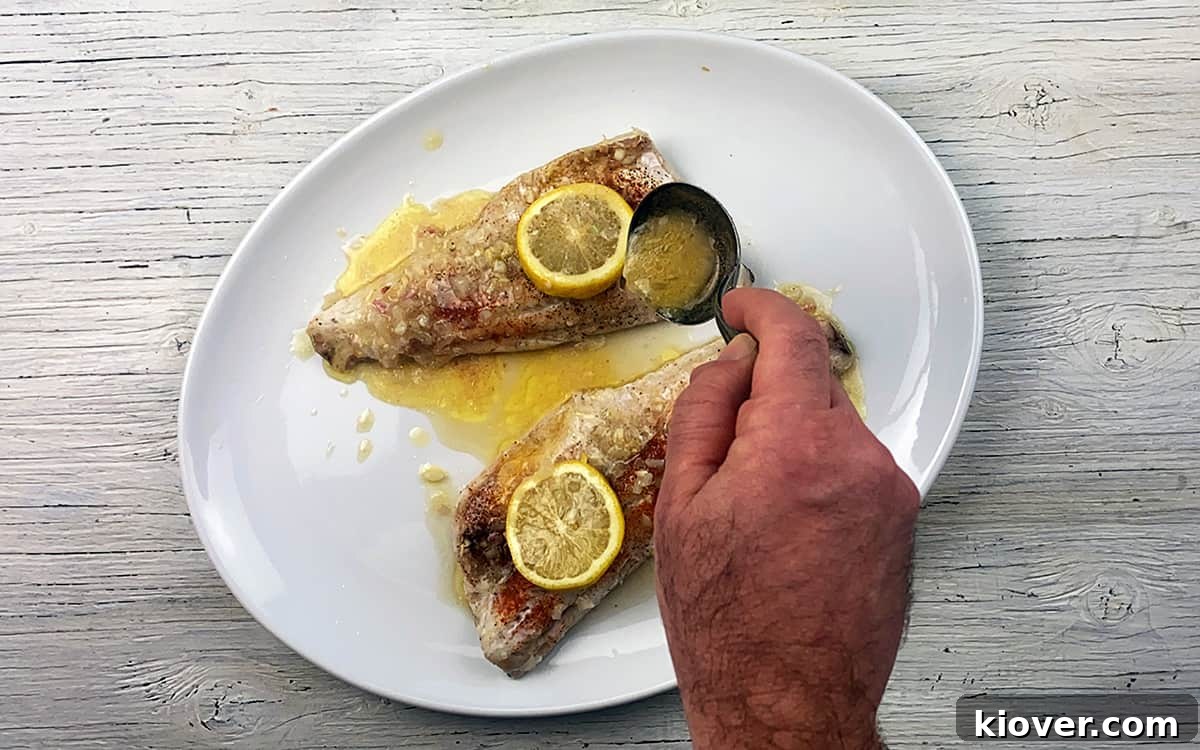 Ladling White Wine Sauce over baked walleye.