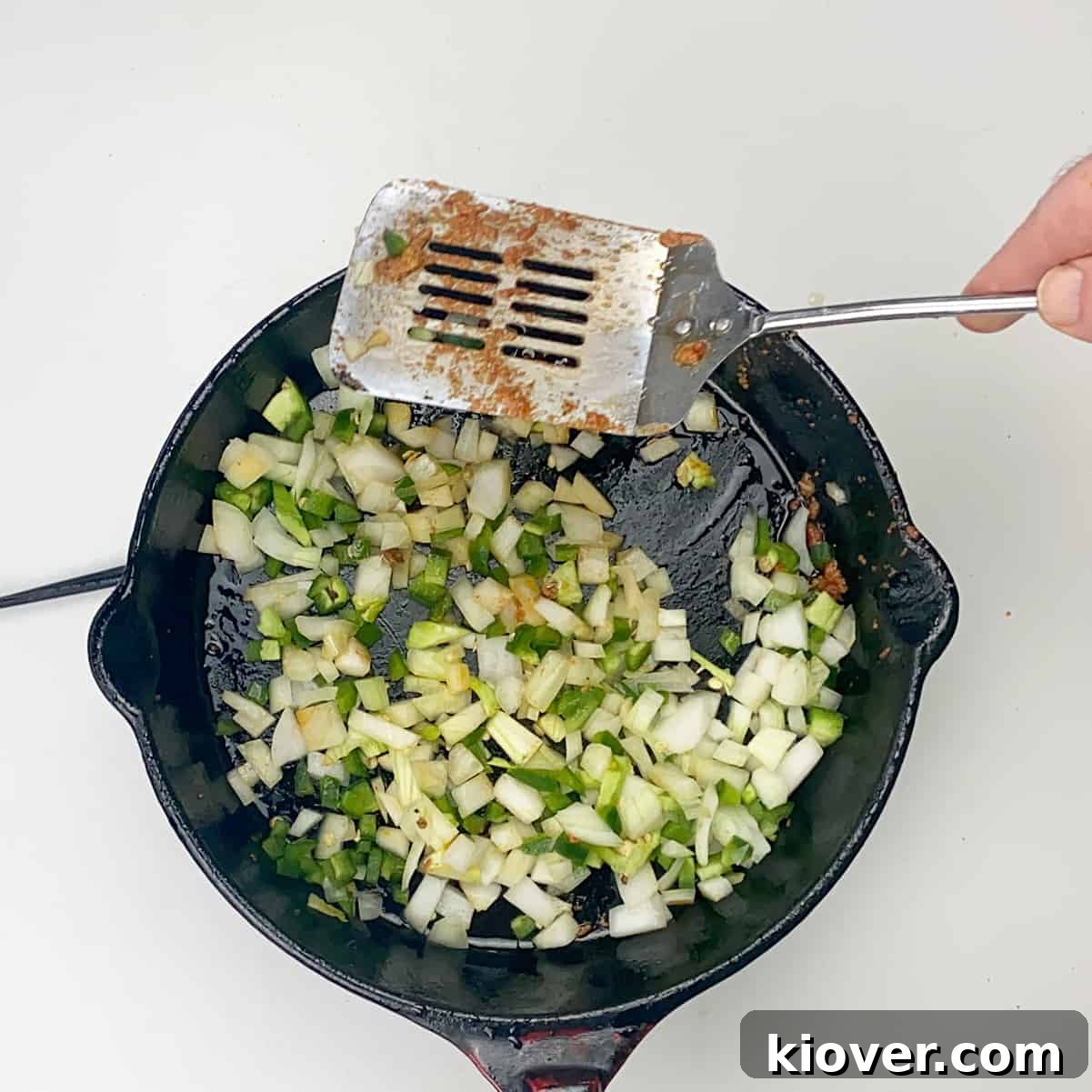 Cooking Onion and Pepper Diced onions and jalapeños cooking in a cast iron skillet, browning gently.