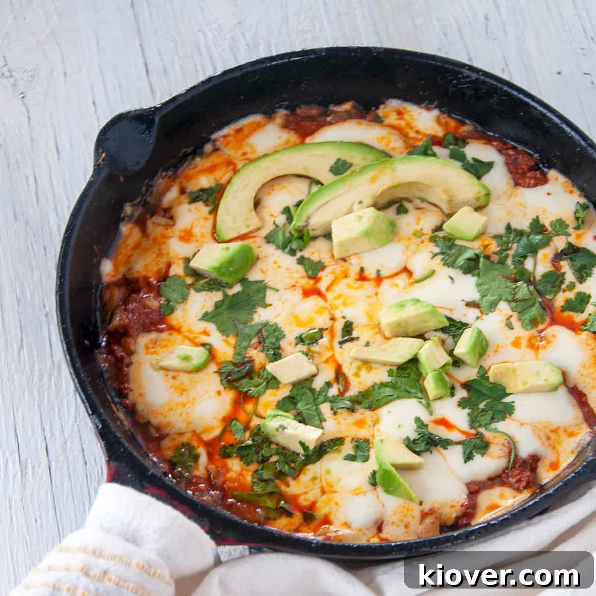 Choriqueso Skillet A cast iron skillet filled with Choriqueso, generously topped with fresh cilantro and sliced avocado, ready to be served.