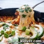 A spoon lifting up some choriqueso from the skillet and the cheese pulling.